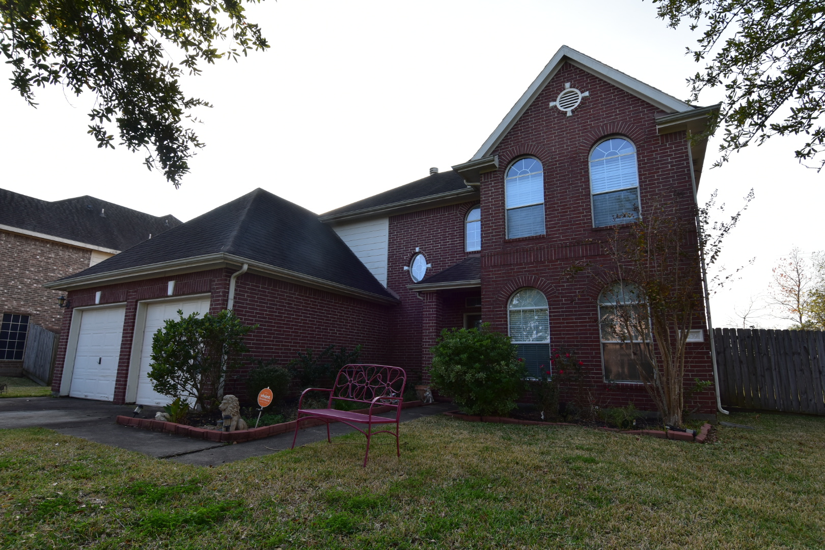 Before — red brick two-story home before professional painting in the Baytown area