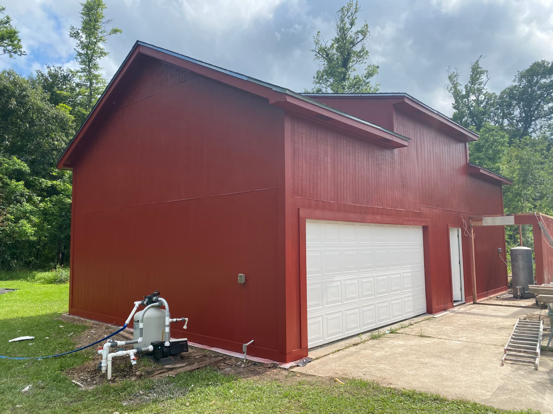 After — same barn and garage with fresh red exterior paint in the Baytown area