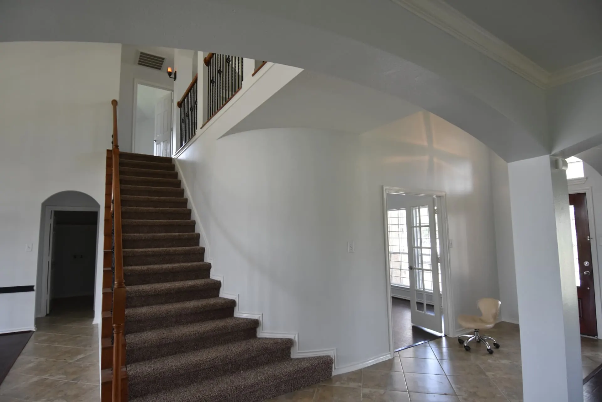 Spacious home foyer and staircase with white walls, ready for interior painting